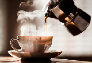 moka pot pouring hot coffee into cup